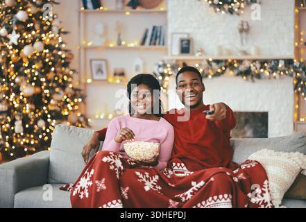 La coppia ama la serata del cinema a casa durante le vacanze, con spuntini e decorazioni intorno Foto Stock