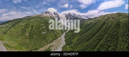 Vista aerea del Caucaso vicino a Ushba e al ghiacciaio Chalaadi a Svaneti, Georgia. Vette innevate, una lingua glaciale grigia e un fiume roccioso che scorre sotto Foto Stock