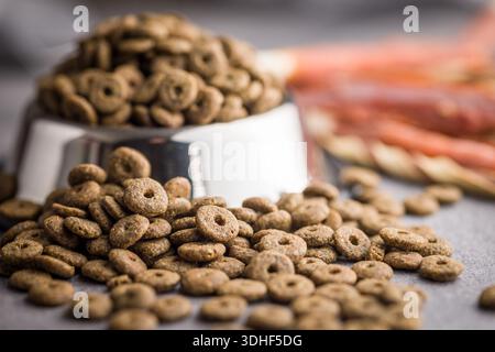 Cibo per animali domestici asciutto. Asciugare il cibo kibble su un tavolo grigio. Foto Stock