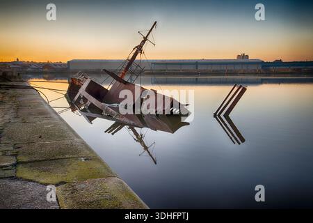 Scafo arrugginito del relitto Sarsia parzialmente sommerso in acqua presso East Float Dock a Birkenhead Foto Stock