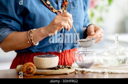 Donna che prepara il tè Blue Matcha e lo setaccia attraverso Un Strainer Foto Stock