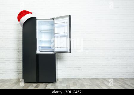 Frigorifero con cappello di Babbo Natale rosso in camera. Spazio per il testo Foto Stock