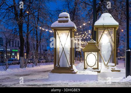 Ulyanovsk, Russia - 14 febbraio 2022: Enormi lanterne di Natale in strada nell'illuminazione serale. Strada ricoperta di neve con decorazioni natalizie. Foto Stock