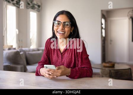 Allegra donna che usa lo smartphone con occhiali alla moda che reggono il telefono cellulare Foto Stock