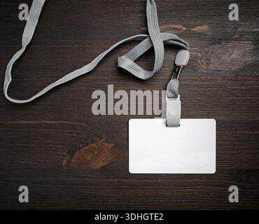 Badge id in plastica vuoto con cordone su superficie in legno. Scheda id vuota. Posizione piatta. Foto Stock