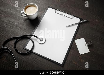 Concetto di assistenza sanitaria. Appunti, stetoscopio, badge, penna e tazza da caffè vuoti su una superficie in legno. Foto Stock