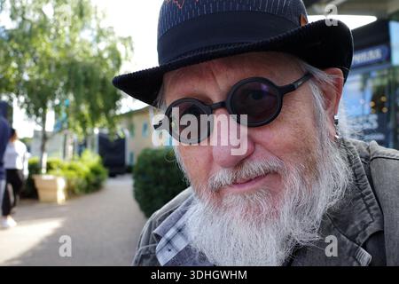 L'uomo anziano con la barba indossa occhiali neri rotondi e un cappello da bowler. Guarda direttamente la telecamera con un leggero sorriso. Le funzioni di sfondo Foto Stock