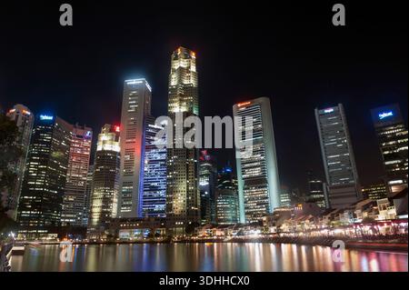 Singapore grattacieli del quartiere degli affari si riflette nel fiume Singapore di notte. Foto Stock