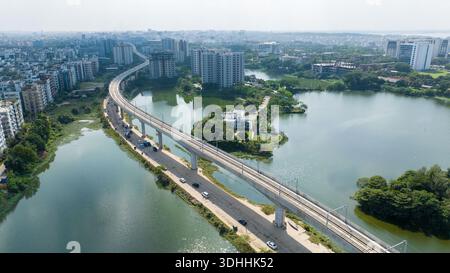 Veduta aerea di dia Bari Road, dove la linea sopraelevata della metropolitana taglia il paesaggio, riflettendo nell'acqua, Dacca, Divisione di Dacca, Bangladesh. Foto Stock