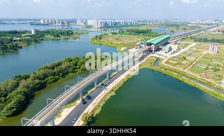 Vista aerea dei binari sopraelevati che attraversano le acque ondulate, la vegetazione verde e gli edifici vicino a dia Bari Road, Dacca, Divisione di Dacca, B. Foto Stock