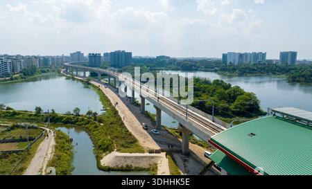 Vista aerea di una moderna ferrovia sopraelevata della metropolitana che attraversa le tranquille acque di un lago, in contrasto con lo skyline della città, Dacca, Dacca Divisione, B. Foto Stock