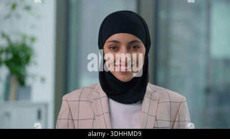 Ritratto in ufficio felice sorridente toothy araba etnica musulmana donna d'affari che guarda la macchina fotografica sorridere spensierata indiano islamica imprenditrice soddisfatta Foto Stock