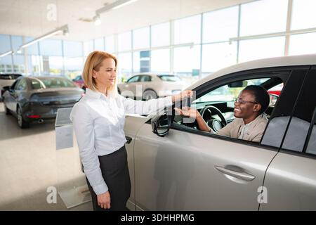 Il venditore di auto consegna la chiave dell'auto al cliente soddisfatto Foto Stock