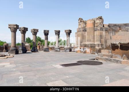 Antiche rovine della cattedrale di Zvartnots con colonne iconiche e capitelli di aquile sotto un cielo azzurro limpido in Armenia Foto Stock