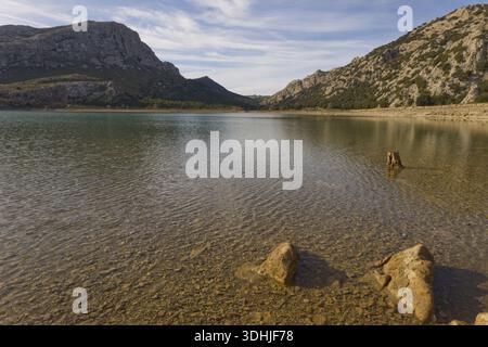Pietre sul litorale del bacino idrico di Cúber nelle montagne della Serra de Tramuntana, Maiorca, sotto un cielo blu con nuvole. Foto Stock