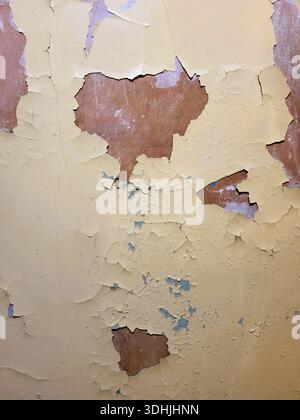 Sfondo texture: Vernice gialla molto vecchia incrinata e blister sul muro di un edificio residenziale che necessita di riparazione Foto Stock