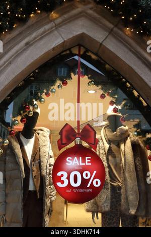 SALDI invernali - Prozentzeichen - leuchtende Weihnachtsgirlande - Rote Weihnachtskugel als Schaufensterdeko mit roter Schleife und Schriftzug: SALE bis zu 30 Prozent auf Winterware - 05.12.2025, Fulda, Deutschland, GER, DEU - Sonderverkauf in einem luxuriösen Einzelhandelsgeschäft Fußgängerzone der Textilbranche in der Innender Fuldaer Fuldaer Fuldaer Fuldstadt. *** Cartello di percentuale di VENDITA invernale illuminato Christmas garland Red Christmas Ball come decorazione vetrina con nastro rosso e lettere VENDITA fino al 30% di sconto su beni invernali 05 12 2025, Fulda, Germania, GER, DEU vendita speciale in un negozio al dettaglio di lusso nel Foto Stock