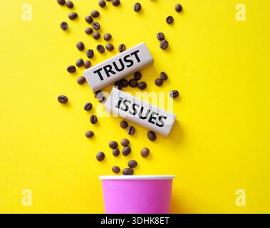 Simbolo dei problemi di fiducia. Blocchi di legno con parole problemi di fiducia. Splendido sfondo giallo con tazza di caffè e chicchi di caffè. Business and Trust Issues co Foto Stock