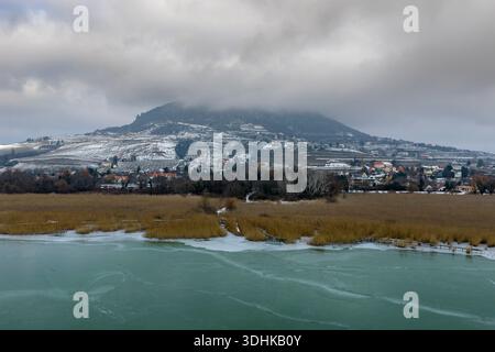 A causa del clima freddo insolito, l'inverno il lago Balaton è congelato a 2026. Colori, forme e formule sorprendenti sono in questa foto. Badacsony hil è su t Foto Stock