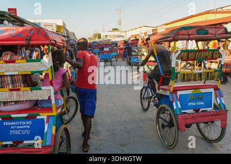 Toliara, Madagascar - 1° maggio 2019: Passeggiata pomeridiana su una tipica strada cittadina di medie dimensioni, bancarelle di mercato su entrambi i lati, gente malgascia che cammina, mese Foto Stock