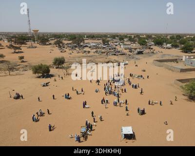 La vista aerea di un vivace mercato si dispiega sotto l'ampio cielo, con venditori e acquirenti che si radunano tra il paesaggio sabbioso, Dodji, Foto Stock