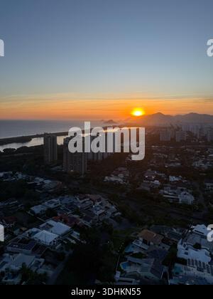 Tramonto sugli alti edifici costieri e sulla laguna con un caldo bagliore all'orizzonte e un paesaggio urbano aereo. Foto Stock