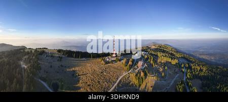 Veduta aerea di una torre rossa e bianca che penetra nella fresca aria mattutina sopra il monte Schöckl, Graz, Stiria, Austria. Foto Stock