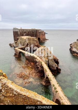 Storica fortezza costiera su un'isola collegata da una strada rialzata in pietra sul mare calmo. Foto Stock