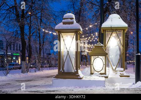 Ulyanovsk, Russia - 14 febbraio 2022: Enormi lanterne di Natale in strada nell'illuminazione serale. Strada ricoperta di neve con decorazioni natalizie. Foto Stock