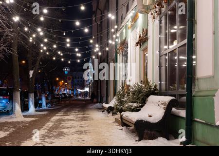 Ulyanovsk, Russia - 14 febbraio 2022: Ghirlande e panchine di Capodanno su una strada della città coperta di neve. Strada ricoperta di neve con decorazioni natalizie. Foto Stock