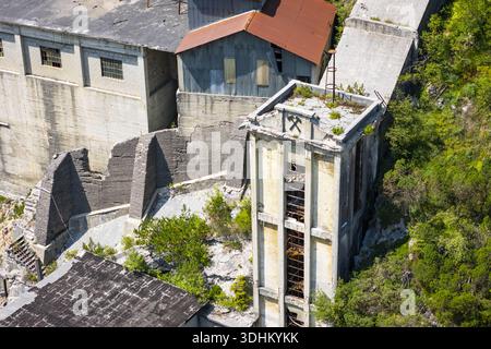 Veduta aerea degli edifici duri e intemprati della Cave del Predil si stagliano in silenzioso contrasto con il vivace fogliame verde, Rabelj, Friuli-Venezia Gi Foto Stock