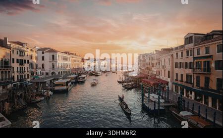 Un pittoresco tramonto illumina il cielo sull'iconico Canal grande di Venezia, riflettendo sull'acqua e proiettando un caldo bagliore sugli storici circostanti Foto Stock