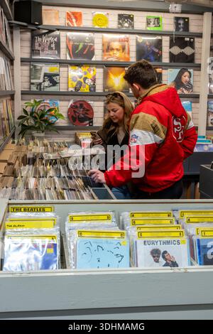 Giovane coppia che sfoglia e guarda i dischi in vinile in un negozio di musica di seconda mano nel mercato di Cardiff, nel centro di Cardiff, Galles, Regno Unito Foto Stock