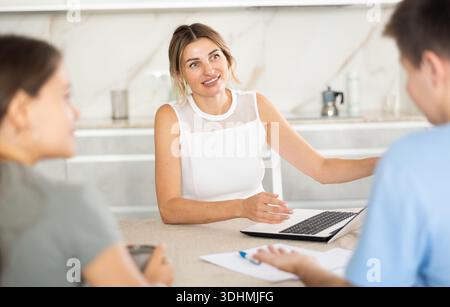 Donna sorridente agente immobiliare che discute con la coppia nell'ufficio dell'agenzia immobiliare Foto Stock
