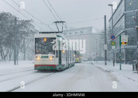 Magdeburgo, Germania - 9 gennaio 2026: Mostra invernale di tram urbano con forti nevicate i trasporti pubblici in funzione condizioni di ghiaccio ridotta visibilità. Neve Foto Stock