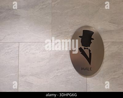 Elegante cartello da toilette maschile con la silhouette di un uomo in un cappello e smoking, montato su una parete di marmo Foto Stock