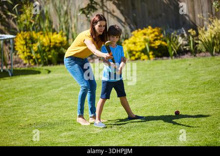Bambino, che gioca e donna con bastone da hockey, all'aperto e allenamento per lo sport con il figlio a casa o in pausa. Cortile, mamma e legame con il bambino nel fine settimana Foto Stock