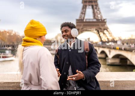 Coppie diverse che viaggiano a parigi parlando sul ponte Foto Stock