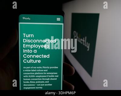 In questa illustrazione fotografica, una persona ha in mano uno smartphone con la pagina Web dell'azienda statunitense di app per social media Phictly sullo schermo davanti al logo. Foto Stock