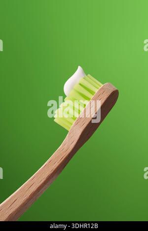 Spazzolino ecologico in bambù con dentifricio su sfondo verde. Foto Stock