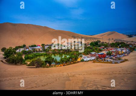 Oasi desertica illuminata di Huacachina al crepuscolo Foto Stock