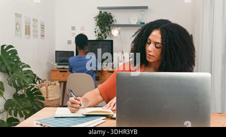 Una donna che lavora con un notebook e scrive in un moderno ufficio Foto Stock