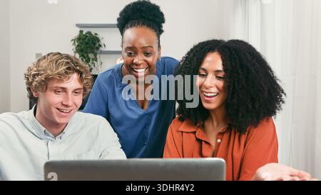 Diverse Trio collabora con un notebook in un ambiente Startup Teamwork Office Foto Stock