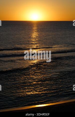 Luce solare dorata sull'acqua increspata Foto Stock