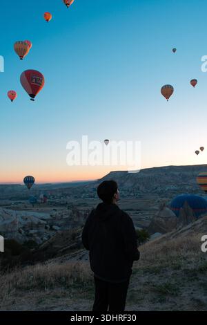Cappadocia, Türkiye - 3 ottobre 2024: Palloni aerostatici fluttuano sul paesaggio roccioso della Cappadocia durante un tour in mongolfiera all'alba Foto Stock