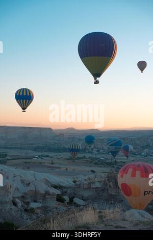 Cappadocia, Türkiye - 3 ottobre 2024: Palloni aerostatici fluttuano sul paesaggio roccioso della Cappadocia durante un tour in mongolfiera all'alba Foto Stock