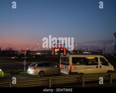 Cremona, Italia 8 gennaio 2026 Un grande complesso commerciale a Cremona, Italia, si illumina di insegne al neon quando i veicoli passano durante l'orario del crepuscolo Foto Stock