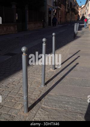 Cremona, Italia 8 gennaio 2026 strada tranquilla a Cremona, Italia, lastricata di ciottoli e fiancheggiata da dissuasori che gettano lunghe ombre in una giornata di sole Foto Stock