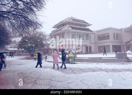 I visitatori camminano attraverso una piazza coperta di neve verso un negozio di souvenir presso il Mausoleo dell'Imperatore Qinshihuang a Xi'an Foto Stock