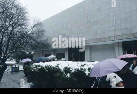 I visitatori fanno la fila sotto gli ombrelli all'esterno di un edificio del museo presso il Mausoleo dell'Imperatore Qinshihuang durante una nevicata Foto Stock
